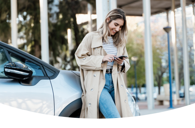 Woman with a phone leaning on a car