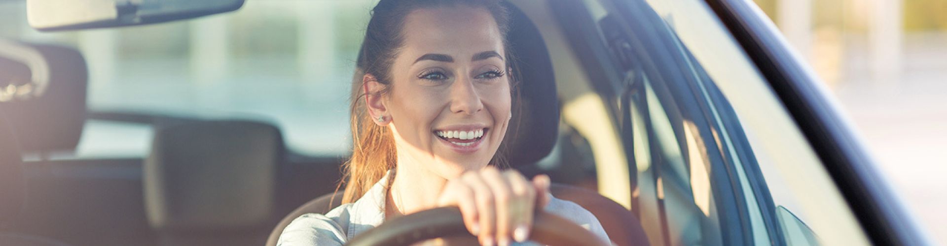 Fröhliche Frau mit Lächeln am Steuer eines Autos