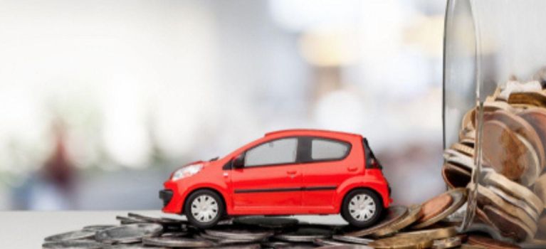 Une voiture miniature rouge sur des pièces de monnaie