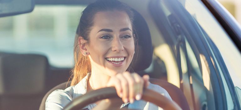 Happy woman with smile at the wheel of a car