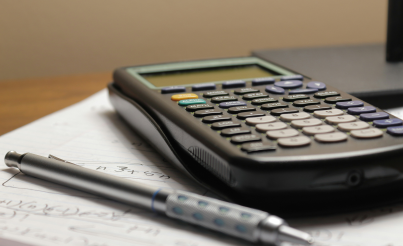 There is a calculator and a pen on a desk that can be used for maths tasks.