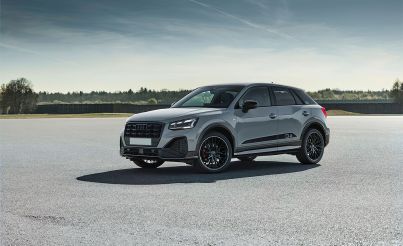 Audi Q2 auf einem breiten Parkplatz mit einem Wald