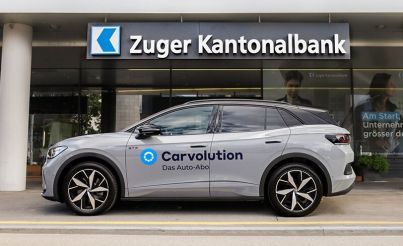 VW ID.4 GTX portant la marque Carvolution devant une banque cantonale de Zug