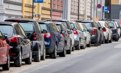 A large number of cars parked on the roadside in an urban environment.