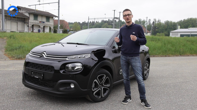 Mann steht vor schwarzem Auto.